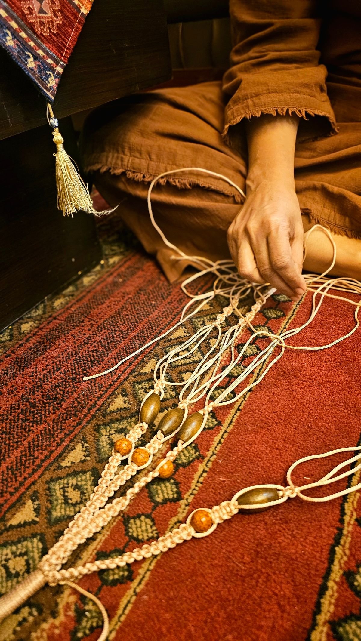 Hands weaving a beaded piece on a loom